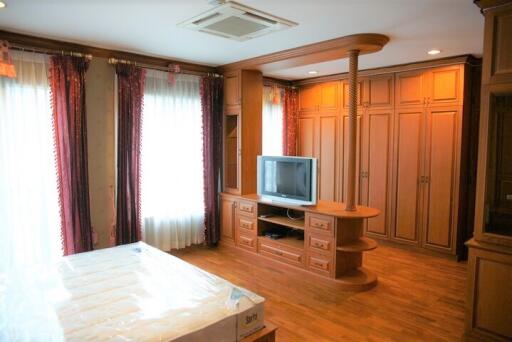 Spacious bedroom with large wooden wardrobe, TV, and a bed