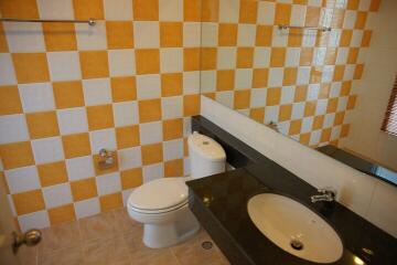 Bathroom with checkered yellow and white tile walls, dark countertop, and a large mirror