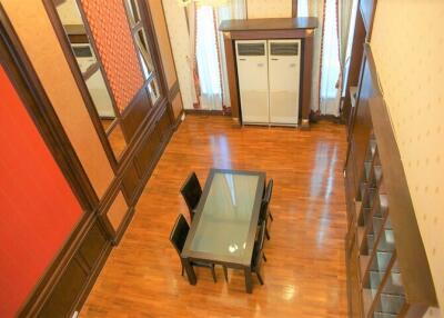 Aerial view of a dining room with wooden flooring, a glass-top dining table, and chairs