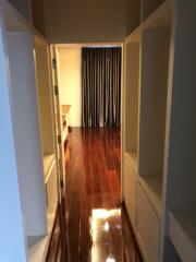 View of a hallway with wooden flooring leading to a room with curtains