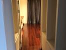 View of a hallway with wooden flooring leading to a room with curtains