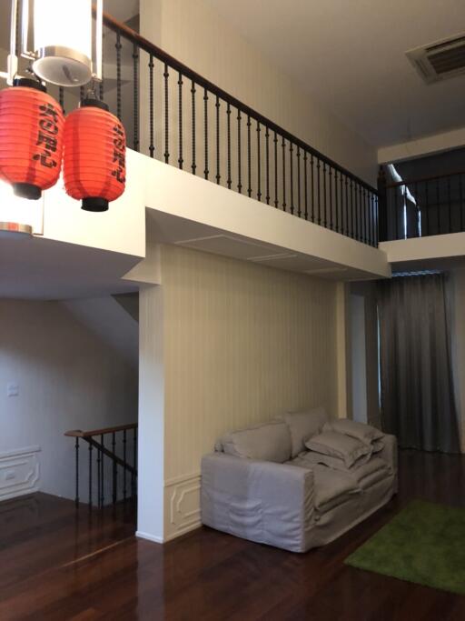 Living room with grey sofa, wooden floor, and red hanging lanterns