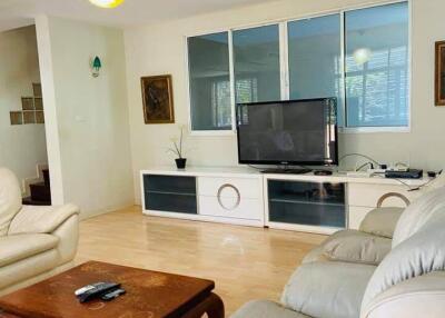 Living room with beige sofas, wooden coffee table, and TV setup