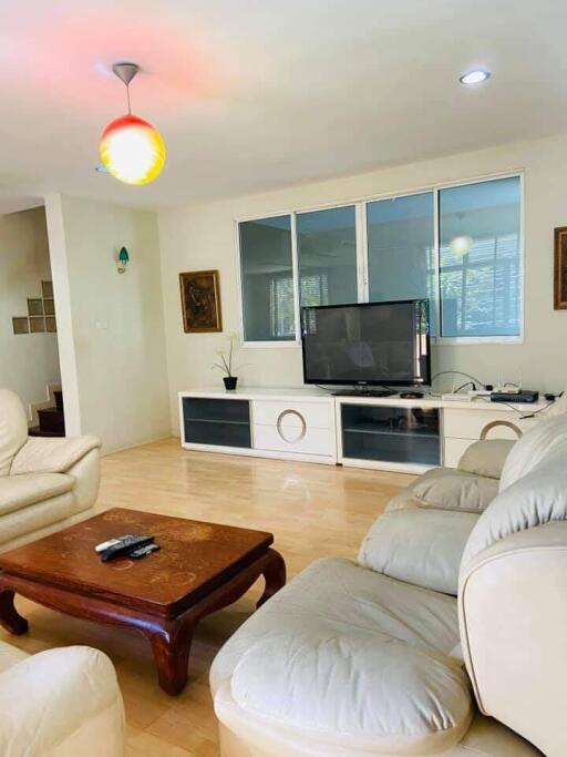 Living room with beige sofas, wooden coffee table, and TV setup