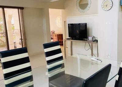 Modern dining area with striped chairs, glass table, and a mounted TV