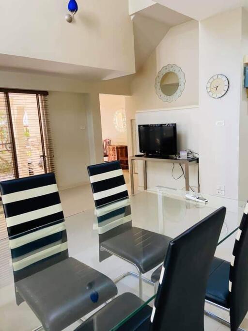 Modern dining area with striped chairs, glass table, and a mounted TV