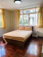 Cozy bedroom with a double bed, windows, and wooden flooring