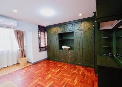 Spacious bedroom with built-in green wardrobes and parquet floors