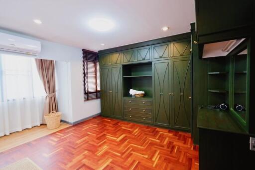 Spacious bedroom with built-in green wardrobes and parquet floors