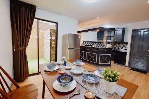 Dining area with a view of the kitchen featuring wooden furniture, a dining table set, and a modern kitchen background.