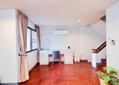 Home office with desk and chair, wooden floors, and large window