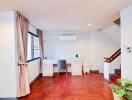 Home office with desk and chair, wooden floors, and large window