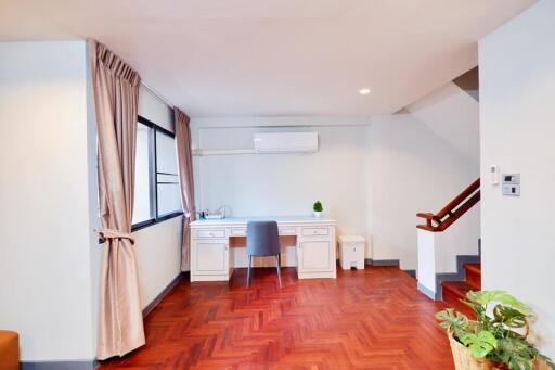 Home office with desk and chair, wooden floors, and large window