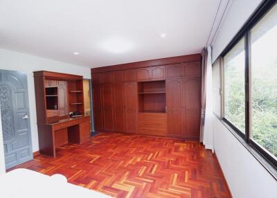 Spacious bedroom with wooden flooring and built-in wooden cabinets