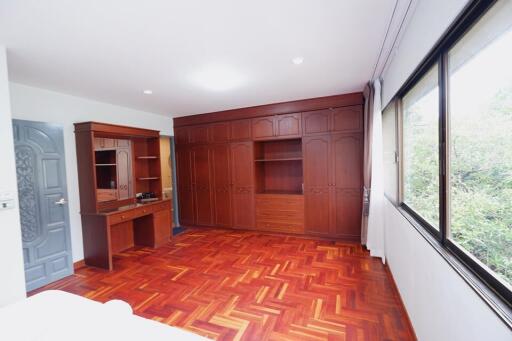 Spacious bedroom with wooden flooring and built-in wooden cabinets