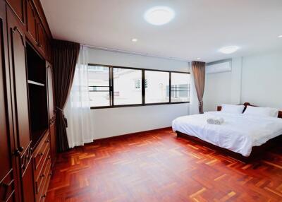 Spacious bedroom with wooden flooring and large windows