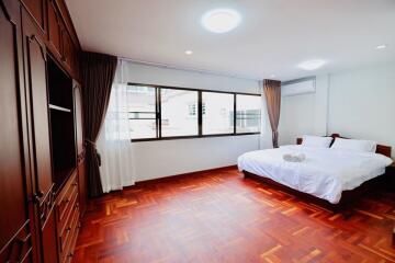 Spacious bedroom with wooden flooring and large windows