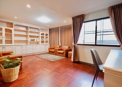 Spacious living room with wooden flooring, built-in shelves, and large windows