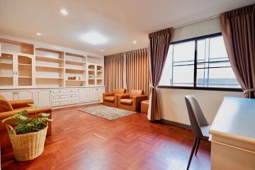 Spacious living room with wooden flooring, built-in shelves, and large windows