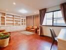 Spacious living room with wooden flooring, built-in shelves, and large windows