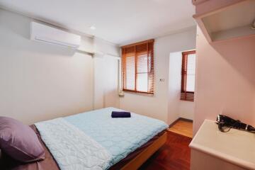 Bright and cozy bedroom with bed, window blinds, and air conditioning unit