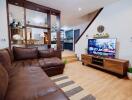 Living room with a brown leather sofa, wooden TV stand, and a view of the kitchen area