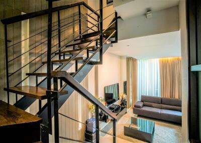 Stylish living room with a modern staircase and large windows.