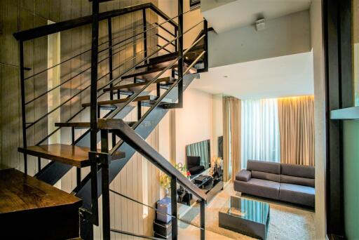 Stylish living room with a modern staircase and large windows.