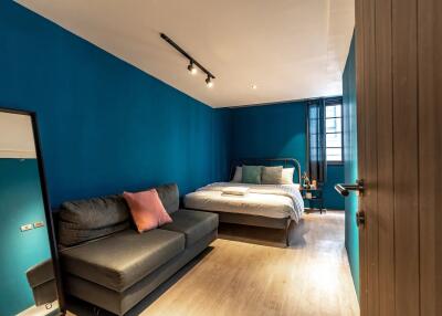 Modern bedroom with blue walls, a bed, and a sofa