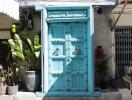 Photo of a bright blue door with metal accents, surrounded by potted plants