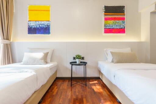 modern bedroom with two single beds, abstract art, and hardwood floor