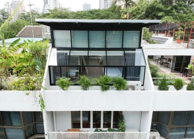 Modern multi-story residential building with balcony and greenery