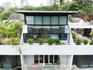 Modern multi-story residential building with balcony and greenery