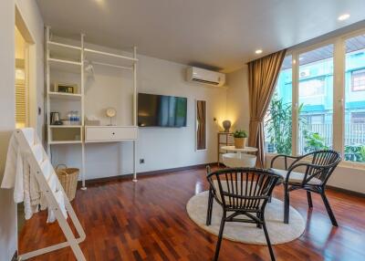 Modern living room with wooden flooring, TV, air conditioner, and seating area