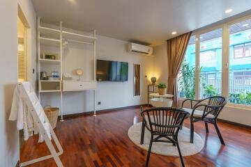 Modern living room with wooden flooring, TV, air conditioner, and seating area