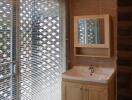 Modern bathroom with sink and mirror, natural light from large window with blinds