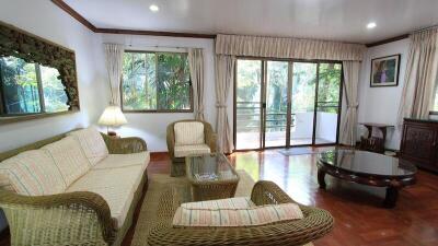 Spacious and well-lit living room with wicker furniture and wooden flooring