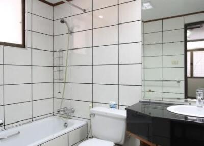 Modern, clean bathroom with white tiles, bathtub, and a vanity with a sink.