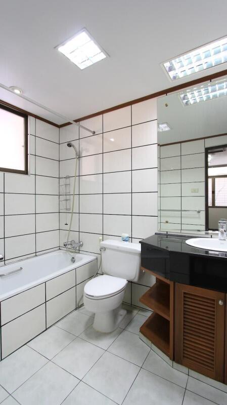 Modern, clean bathroom with white tiles, bathtub, and a vanity with a sink.