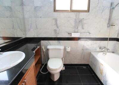 Modern bathroom with black and white tiles, a sink, toilet, and bathtub with shower.