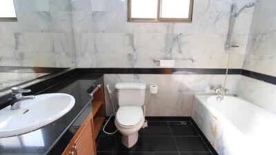 Modern bathroom with black and white tiles, a sink, toilet, and bathtub with shower.