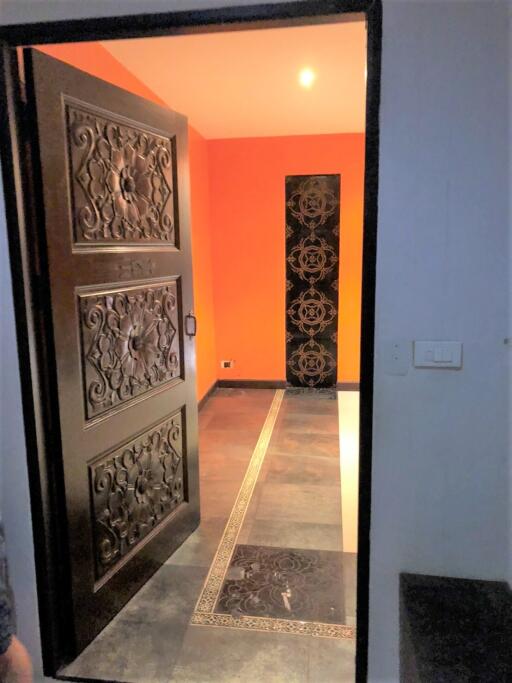 Ornate door at entrance with a view of a small hallway