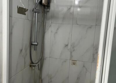 Compact bathroom with tiled shower area and electric water heater