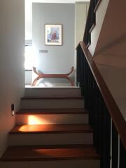 Indoor staircase leading to a landing area with a decorative bench and framed artwork