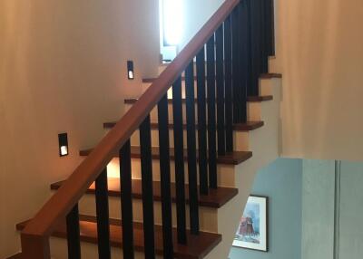 Wooden staircase with railing in a well-lit hallway