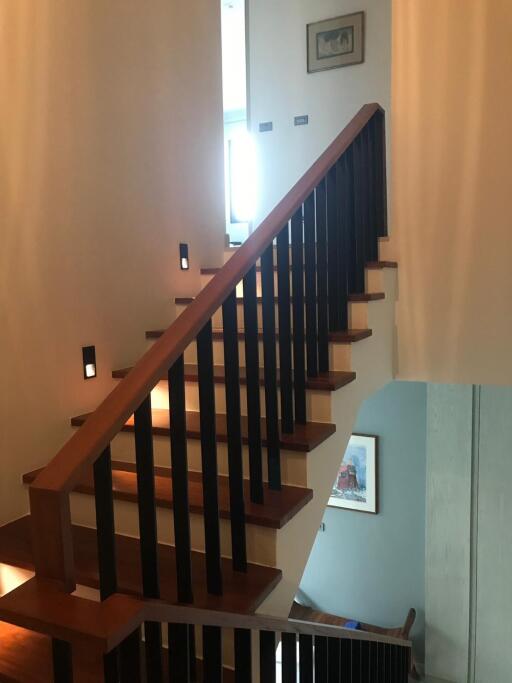 Wooden staircase with railing in a well-lit hallway