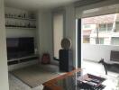 Well-lit modern living room with TV, shelves, and balcony view