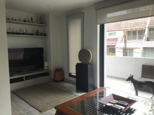 Well-lit modern living room with TV, shelves, and balcony view