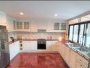 Modern kitchen with stainless steel appliances, wooden flooring, and ample natural light