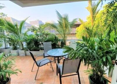 Outdoor patio with chairs, table, and lush greenery